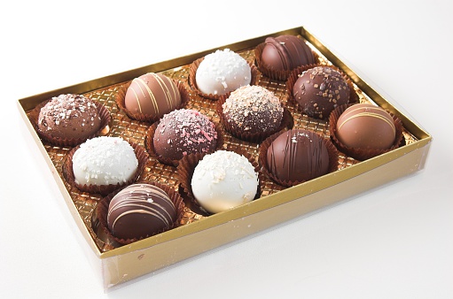 Box of twelve delicious truffles in open gold box on angle