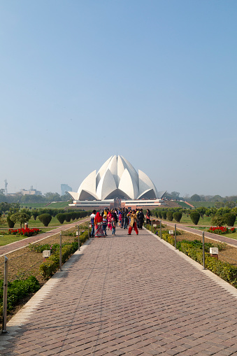 2nd February, 2020 - Delhi, India: Captured in this editorial image is the Lotus Temple, an iconic Bahá'í House of Worship located in South Delhi. Designed to mimic a lotus flower in bloom, the temple is an architectural feat composed of 27 marble petals. The people featured in the photograph are local visitors, seen engaging with the temple's intricate design, taking photographs, and participating in quiet contemplation. The Lotus Temple, renowned for its commitment to inclusivity and openness, serves as a sanctuary for prayer and meditation for people of all faiths. The image captures the essence of communal spirituality amidst the backdrop of this unique structure.