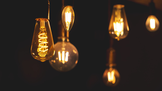 Retro LED light bulbs hanging on a dark background in interior. Electricity, Vintage