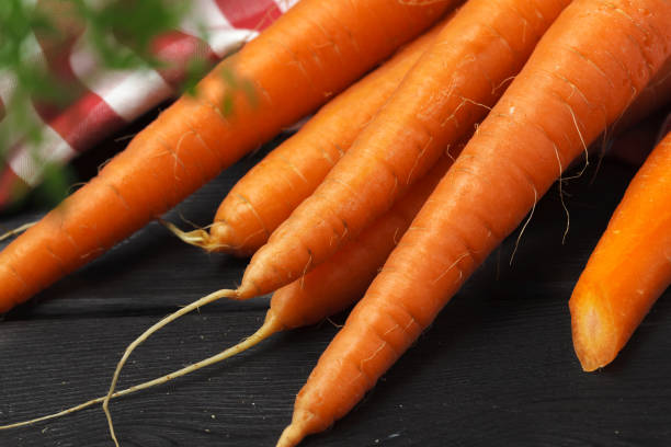 istock Fresh carrot bunch on dark black background top view 1737575941