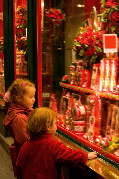 Two children late at night, gazing at a shop-window packed with goodies. Shop is closed though.