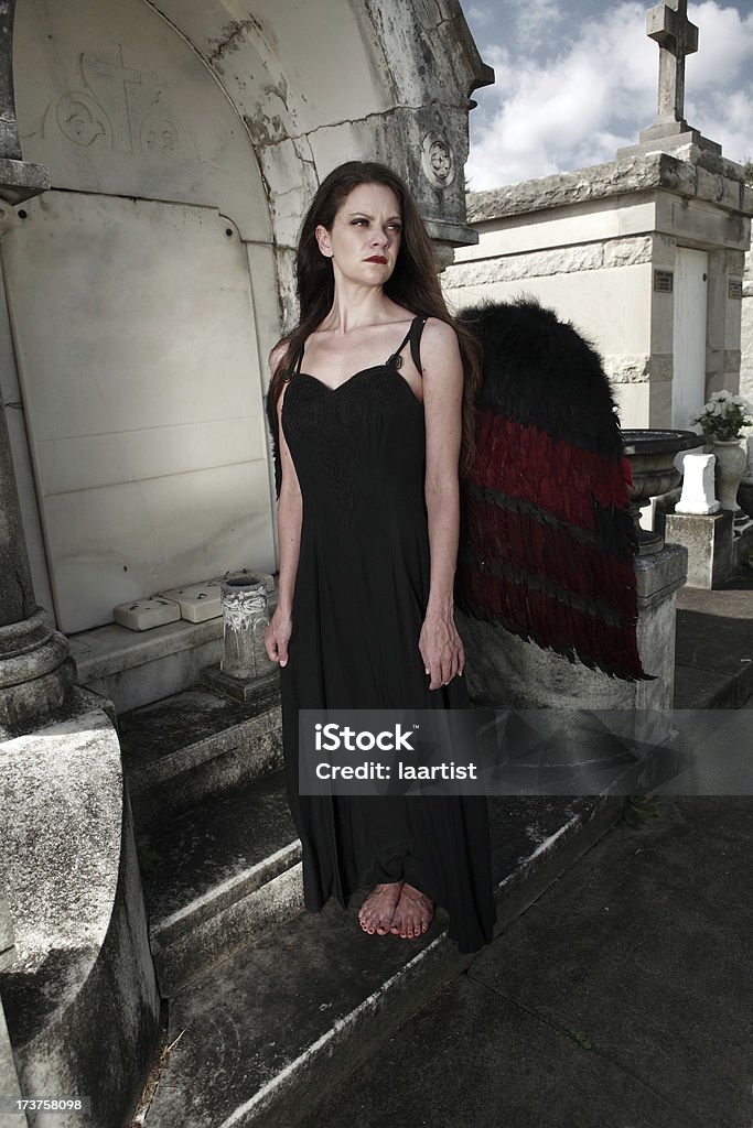 In mourning. A pale woman stands next to a tomb in an old cemetery. Barefoot Stock Photo