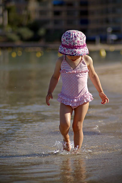 Children holding hands walking on the beach. Rear view.