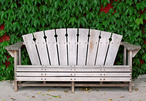 Wooden bench in front of a red wall with greenery