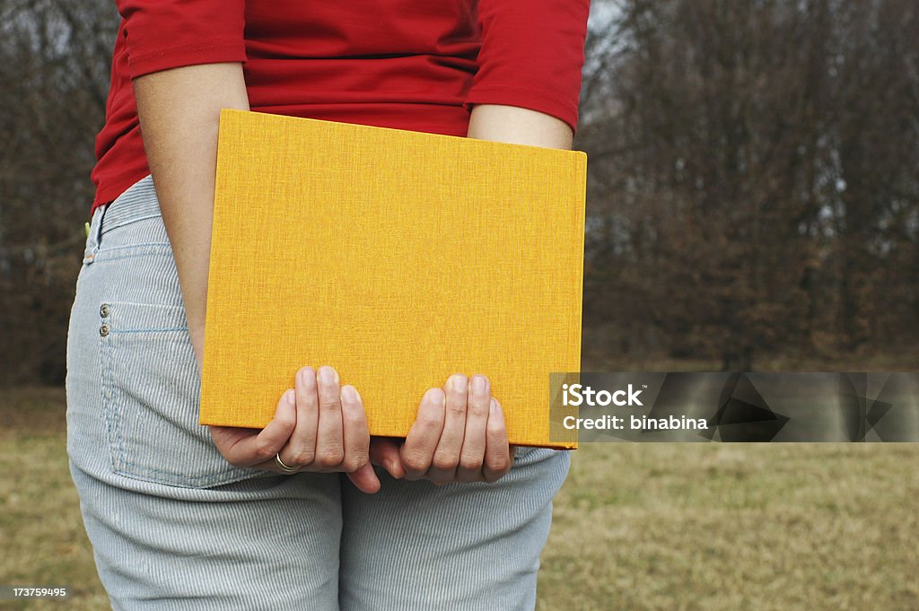 Ragazza tiene un libro giallo - Foto stock royalty-free di Abbigliamento casual