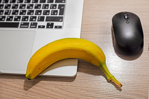 banana on the table near the computer with a computer mouse. snack