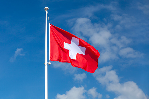 Close-up on the flag of Switzerland waving atop of its pole.