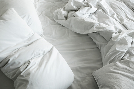Disheveled sheets and pillows of an unmade bed