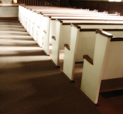 Pews of an old church with sunlight coming in through the window. This is part of a town meeting hall that was on an old Lincoln estate in Indiana