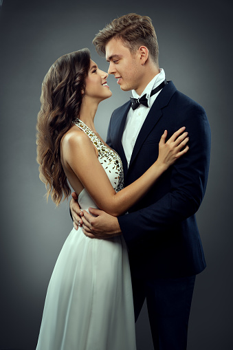 Wedding Couple in Love looking at each other side view. Romantic Bride and Groom Happy embracing. Smiling Elegant Man and Lady over Gray Studio Background