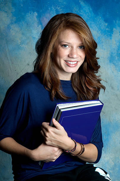 Happy Teen With a Book "Teenager with a color-coordinated book in the studio. Need photos of teens in action, studying, having fun, living life" high school photos stock pictures, royalty-free photos & images