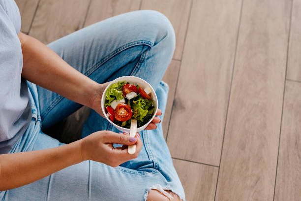 istock Woman eating healthy salad from paper container 1737634905