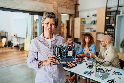 Portrait of smiling mature woman holding circuit board during computer education training class