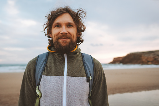 Handsome man portrait curly hair outdoor bearded guy with backpack travel lifestyle active summer vacations