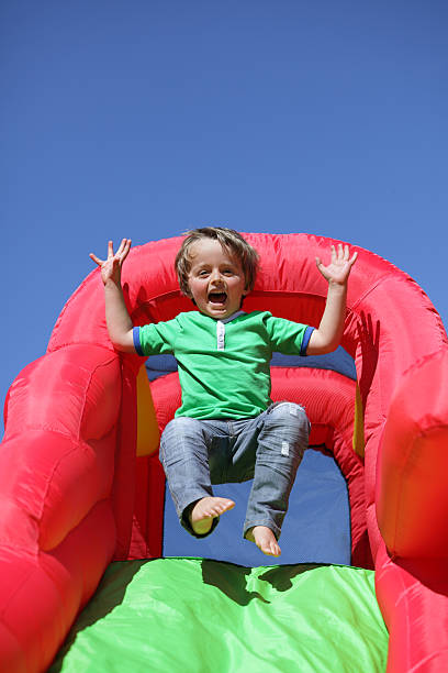 niño en tobogán inflable castillo inflable para saltar - inflatable child playground leisure games fotografías e imágenes de stock