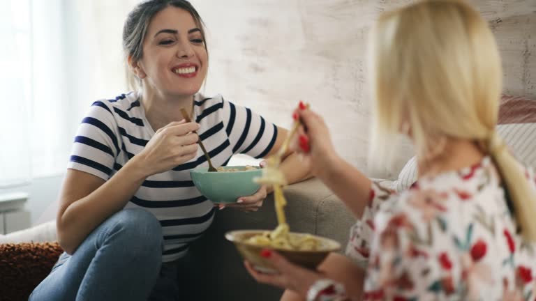 Two girl friends having lunch at home.