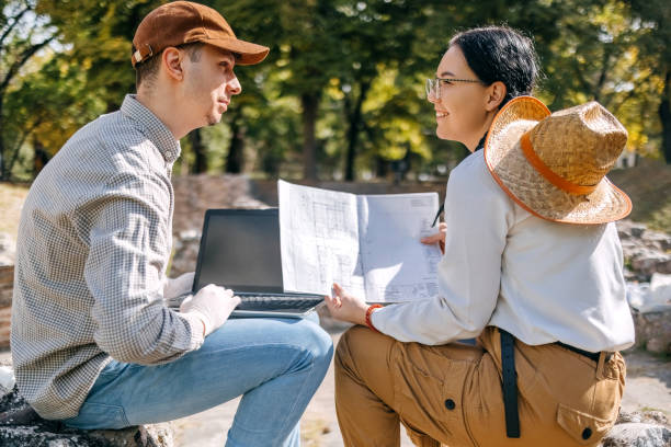 istock Two young colleagues planning for dig using laptop and paper document 1737695661