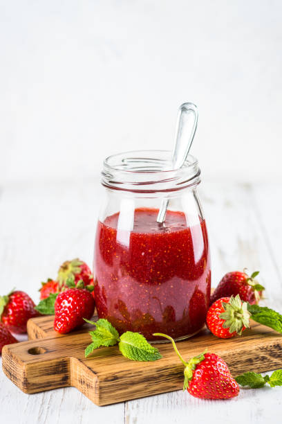 istock Strawberry jam in the glass jar at white table. 1737695670