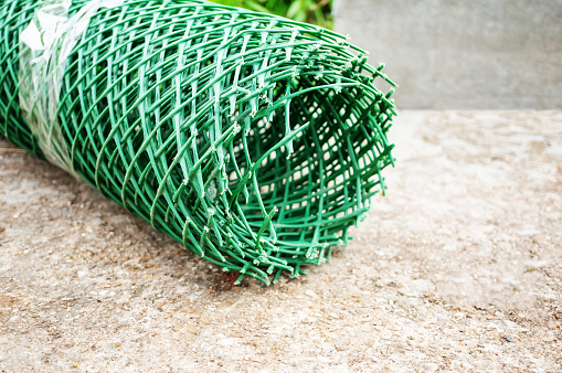 roll of plastic mesh is lying on the lawn. plastic mesh is ready for use in the garden. Copy space.