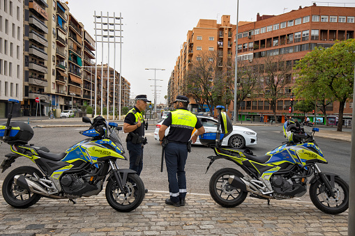 Two police men talking to each other by their motorcycles at sidewalk, Seville, Spain.