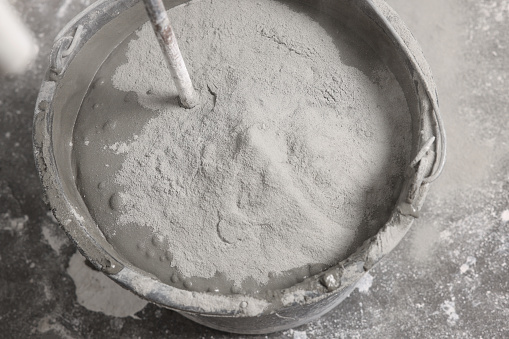 Bucket with concrete and cement powder indoors, closeup