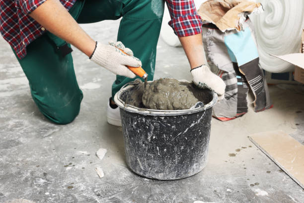 istock Worker with trowel mixing concrete in bucket indoors, closeup 1737732007