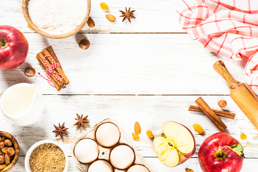 Fall baking. Autumn baking concept. Ingredients for baking - flour, sugar, apples and spices. Top view at white wooden table.