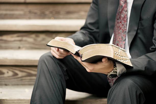 Missionary Sitting on Stairs Reading from the Scriptures A male missionary dressed in a suit sits on wooden stairs and reads from the Scriptures. mormonism photos stock pictures, royalty-free photos & images
