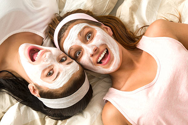 Crazy girls with facial mask lying bed stock photo