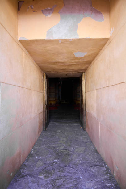 Mysterious Hallway: Journey to the Unknown Narrow hallway with a low ceiling that leads to the entrance to a pyramid. The walls and ceiling are made of an orange-pink plaster. The floor is made of gray stone tiles low viewing point stock pictures, royalty-free photos & images