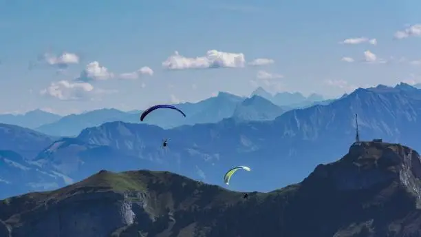Hiking through the Appenzell mountains from Ebenalp in Wasserauen, Switzerland while viewing flying paragliders in the sky