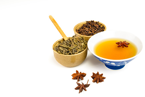 Green tea ready to be drink with star anise and spice cloves over isolated white background.Image made in studio