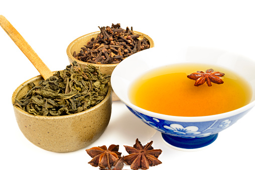 Green tea ready to be drink with star anise and spice cloves over isolated white background.Image made in studio
