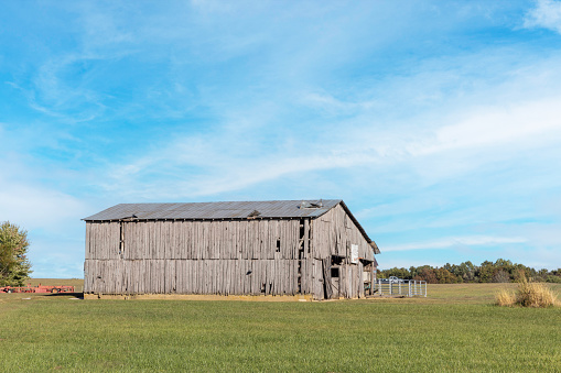 An old wooden barn with sheets of metal bent on the roof.