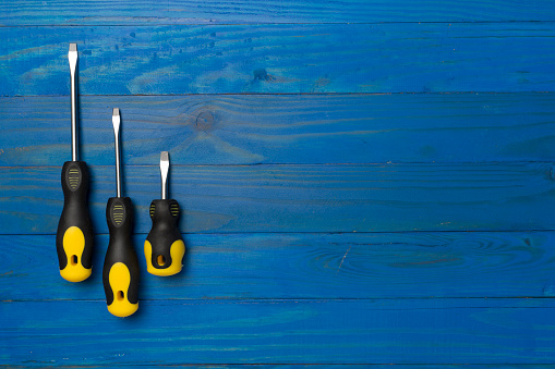 Screwdrivers on wooden background, top view