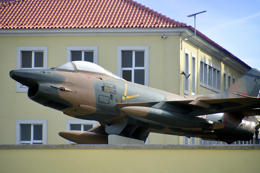 Lisbon, Portugal: retired Fiat G.91 R/3 jet fighter aircraft - without unit or serial markings on public display on a plinth in front of the Military College building - The aircraft was developed by Fiat Aviazione in Italy and was intended to replace the F-86 Sabre within NATO. The “G” stands for Fiat Avio chief designer, Giuseppe Gabrielli. After Fiat Aviazione merged with other Italian aircraft manufacturers to form Aeritalia SpA, the designation changed to Aeritalia G.91 - The aircraft was widely used by the Portuguese Air Force in Africa (Mozambique, Angola and Guinea-Bissau provinces) in a ground attack role. It fought against African terrorist organizations, some financed and supported by the USSR or PR of China (Frelimo, MPLA, UNITA, PAIGC), but also against the FNLA, sponsored by a fellow NATO member, the US under JFK. Some aircraft were lost after the USSR supplied 9K32 Strela-2 light-weight, shoulder-fired, surface-to-air missile (MANPADS) to the terrorists. Ironically the Soviet Air Force would later face similar problems in Afghanistan with the introduction of the FIM-92 Stinger missile in Taliban service.
