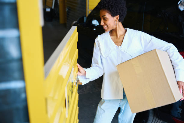 African American woman loading a cardboard box into storage locker