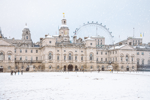 A picturesque scene of the Horse Guards Parade in London blanketed in pristine snow on a winter day. The iconic Horse Guards Building and parade ground are covered in a thick layer of glistening white snow, creating a serene and enchanting atmosphere. The contrast between the historical architecture and the fresh snowfall is truly captivating.\nSnowy day, Horse Guards Parade, London, Winter, Snowfall, Iconic, Historical, Architecture, Snowy Landscape, Glistening, White Snow, Serene, Enchanting, Scenic, London Landmark, London Eye, Snow-Covered, Horse Guards Building, British Architecture, Winter Wonderland