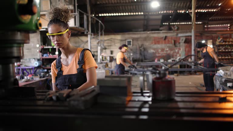 At the metal factory, young female Caucasian metal worker, working on a milling machine