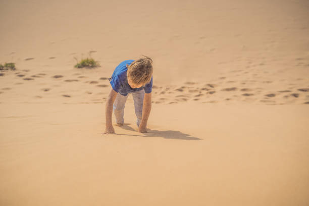 istock Boy overcomes difficulties and aspires to the purpose and dream. Boy overcomes difficulties in life as if in a desert 1737905562