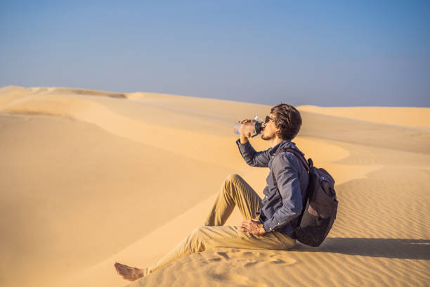 l’homme ressent la soif et boit l’eau dans le désert - thirsty desert men reaching photos et images de collection
