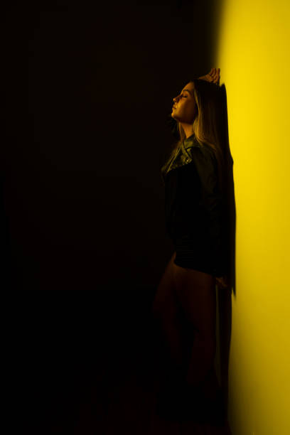 istock A young model woman leaning against a yellow -illuminated wall. 1737942235