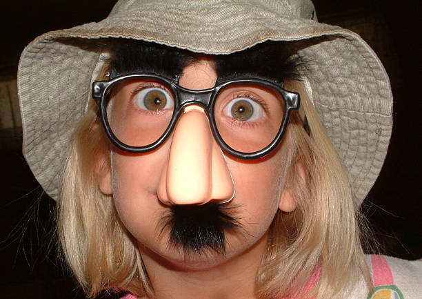 Funny Face 1 photo of a girl wearing a groucho mask. dark backgroud. For more like this checkout groucho marx disguise stock pictures, royalty-free photos & images