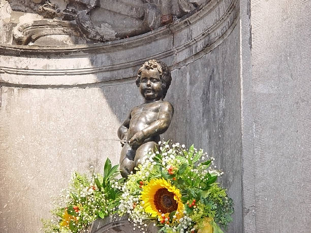 Manneken Pis statue in Brussels with flowers "The infamous Manneken Pis statue in Brussels, with sunflowers." manneken pis statue in brussels belgium stock pictures, royalty-free photos & images