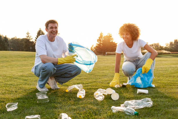 group of multiracial people in gloves and with garbage bags remove plastic and garbage in the park group of multiracial people in gloves and with garbage bags remove plastic and garbage in the park, team of volunteers work and collect plastic bottles, people care about the environment, green planet earth day clean up stock pictures, royalty-free photos & images