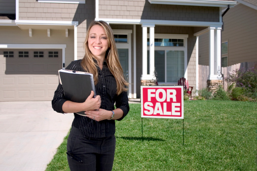 Real Estate Agent standing in front of house for sale