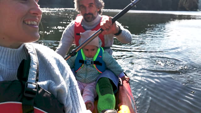 Family kayaking and camping at lake.