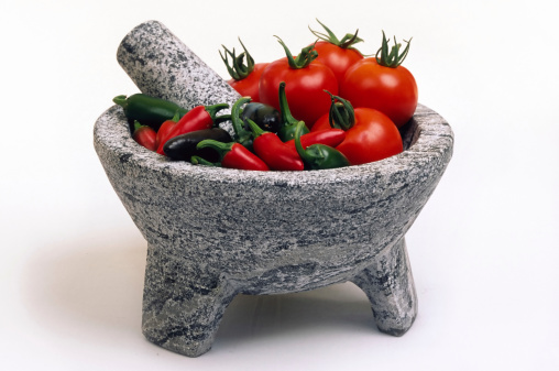 Tomatos and chilie peppers in a marble mortar with pestle