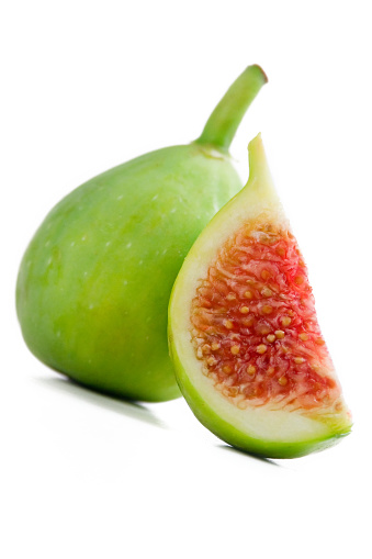 Fresh, delicious fruits of Eden.  A whole ripe green fig and a juicy slice of fig.  Shallow dof