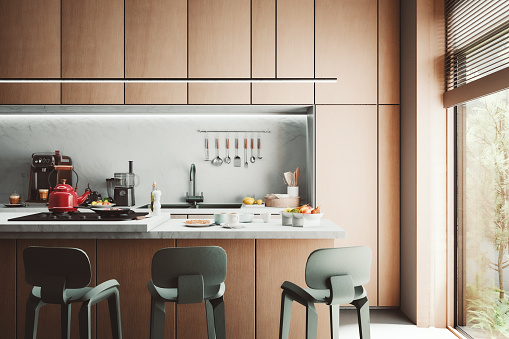 Empty modern kitchen on hardwood floor with white wooden kitchen cabinets, black and white marble background and a large window on a side. Utensils, potted herbs, spices and stoves on kitchen counter. 3D rendered image.